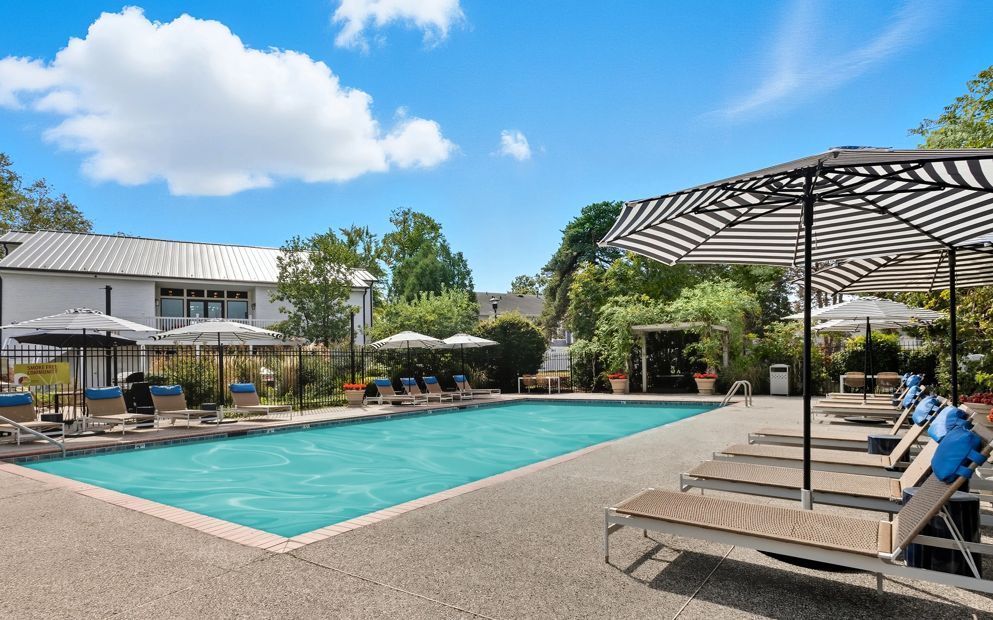 Inviting outdoor pool area with chic striped umbrellas and comfortable loungers under a bright blue sky.