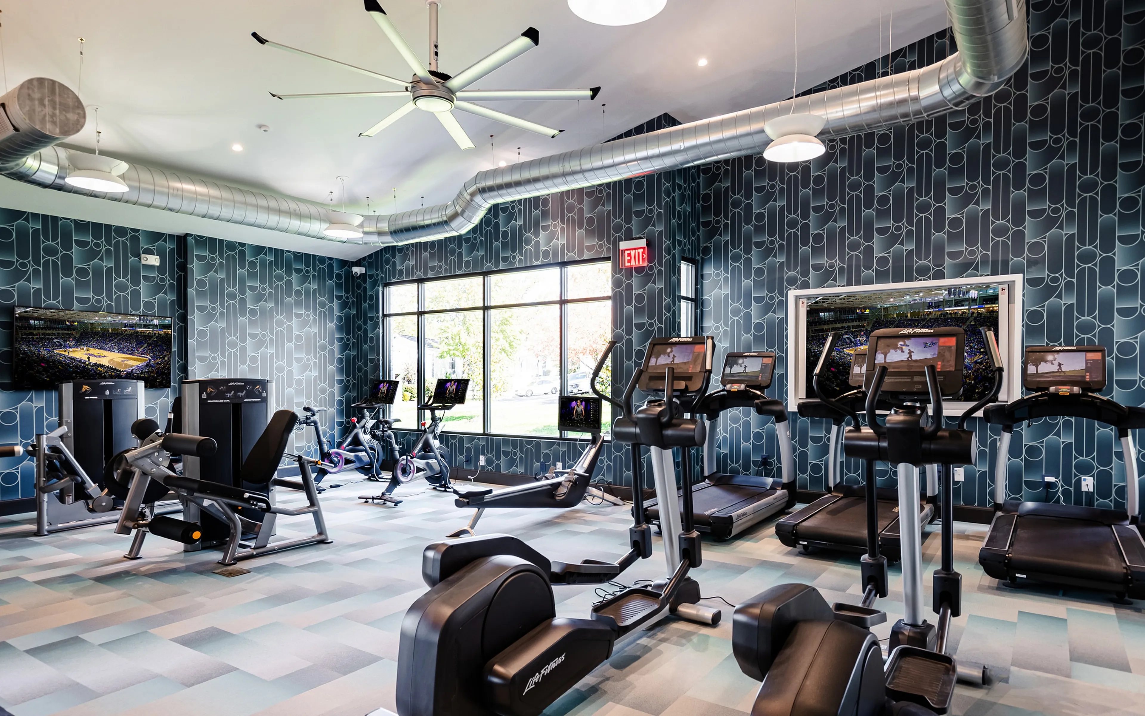 Modern fitness center with state-of-the-art cardio machines, vibrant decor, and bright natural lighting.