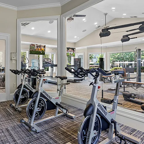 Modern apartment fitness center with state-of-the-art spin bikes, ample natural light, and vibrant decor for energized workouts.