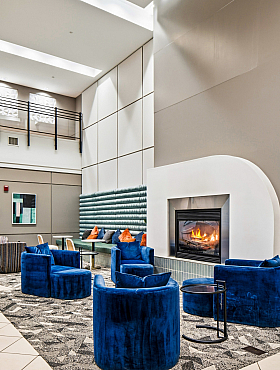 Elegant and modern lobby with a cozy fireplace, plush blue seating, and stylish decor, perfect for relaxation.