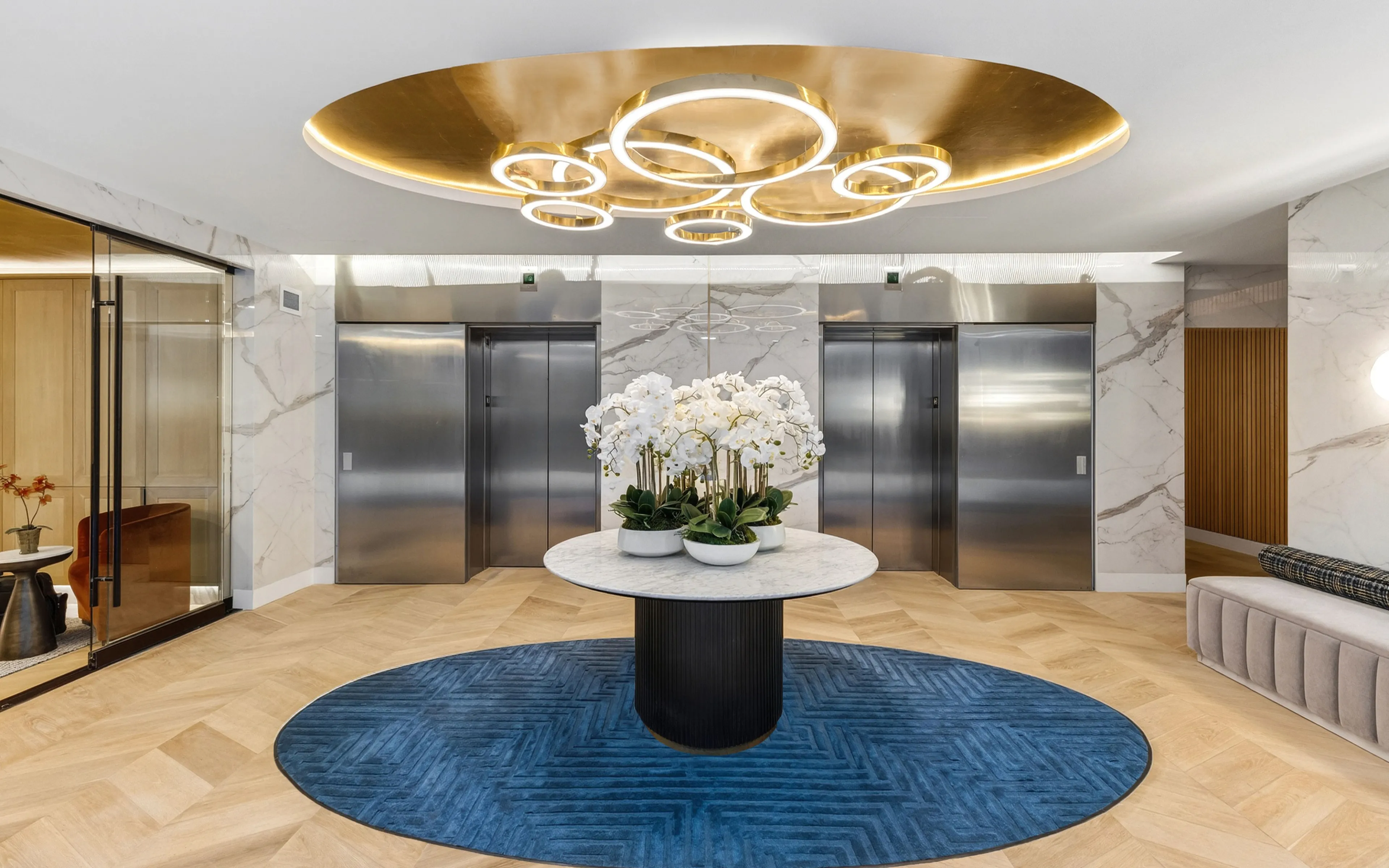 Elegant apartment lobby with a chic marble centerpiece, modern lighting, and stylish elevators, exuding luxury and sophistication.