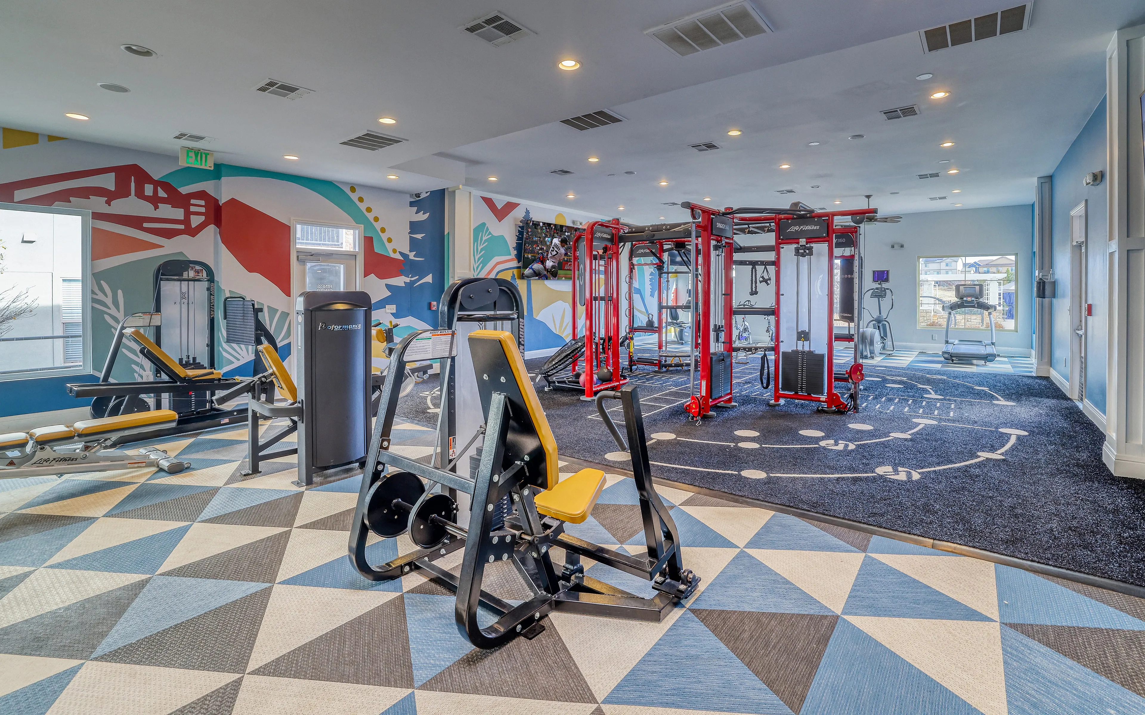 Vibrant modern gym with colorful mural walls, state-of-the-art workout equipment, and ample natural light.