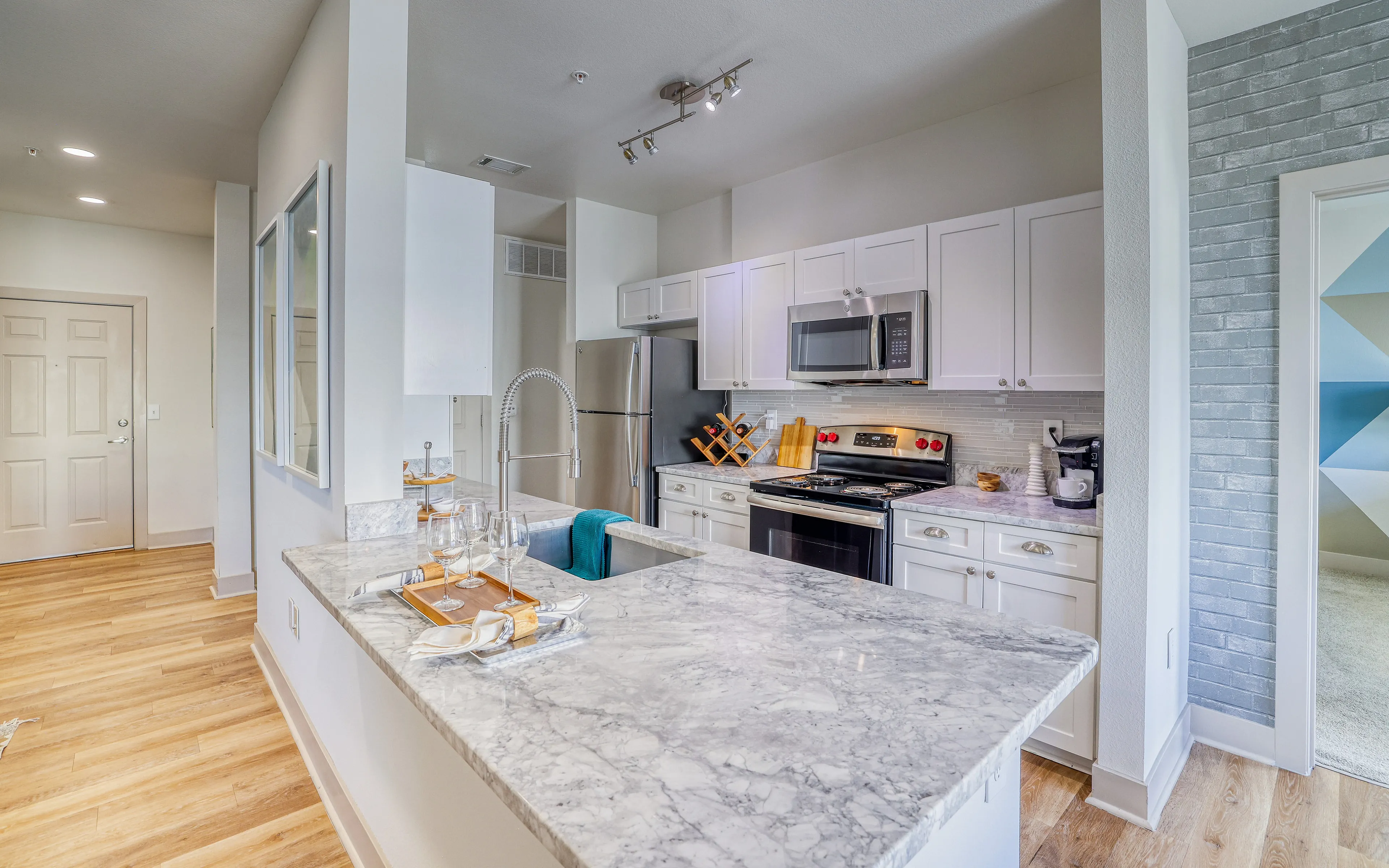 Modern kitchen with sleek marble countertops, stainless steel appliances, and inviting hardwood floors, perfect for culinary creativity.