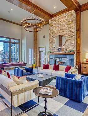 Luxurious living area with high ceilings, expansive windows, and elegant stone fireplace, featuring plush seating and modern decor.