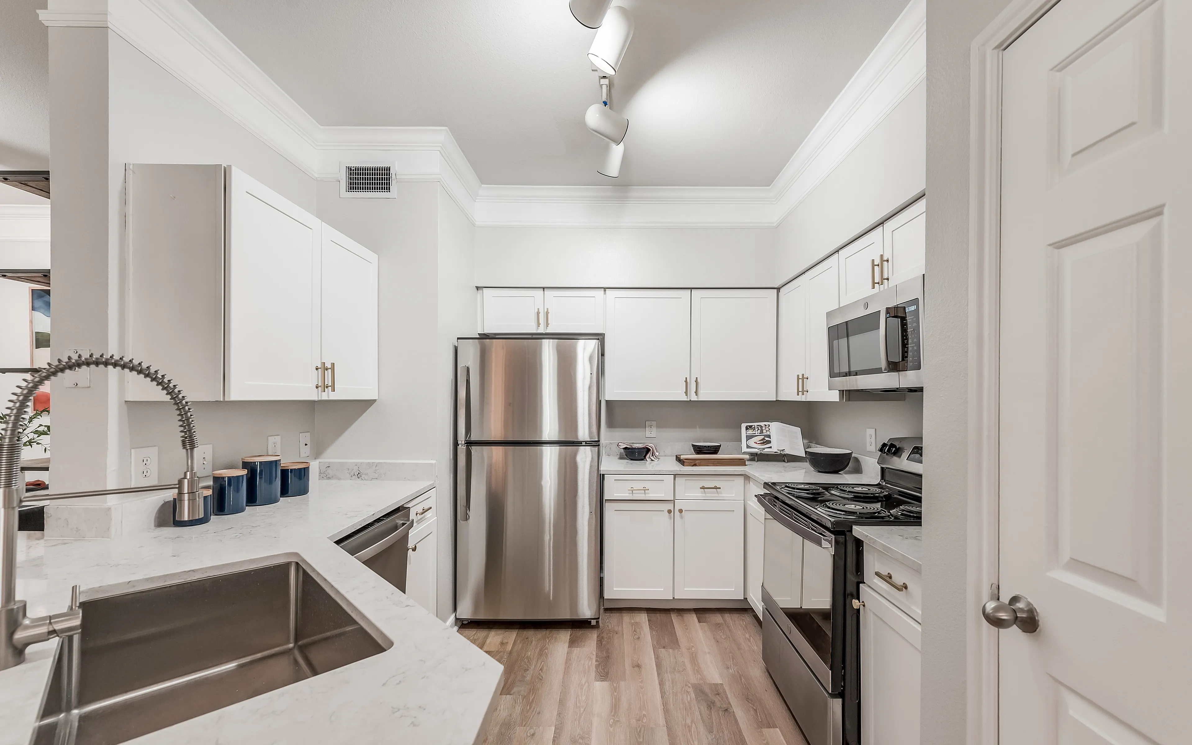 Modern kitchen with sleek stainless steel appliances, elegant white cabinetry, and a spacious marble countertop.