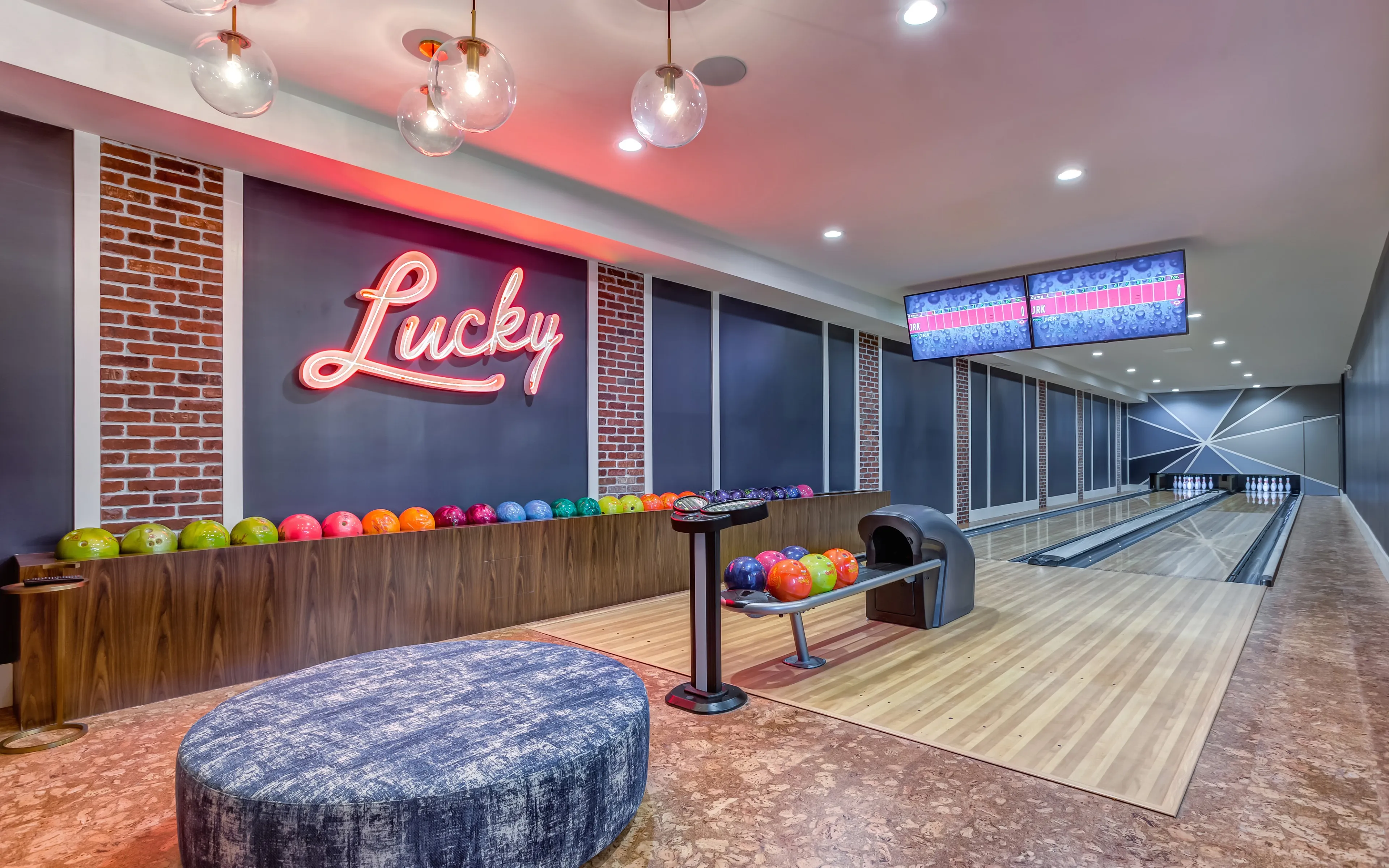 Chic in-apartment bowling alley featuring vibrant bowling balls, sleek wooden lanes, and stylish lighting under a neon sign.