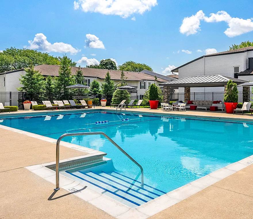 Inviting outdoor pool area with stylish lounge chairs and vibrant umbrellas, perfect for relaxation in a serene residential setting.