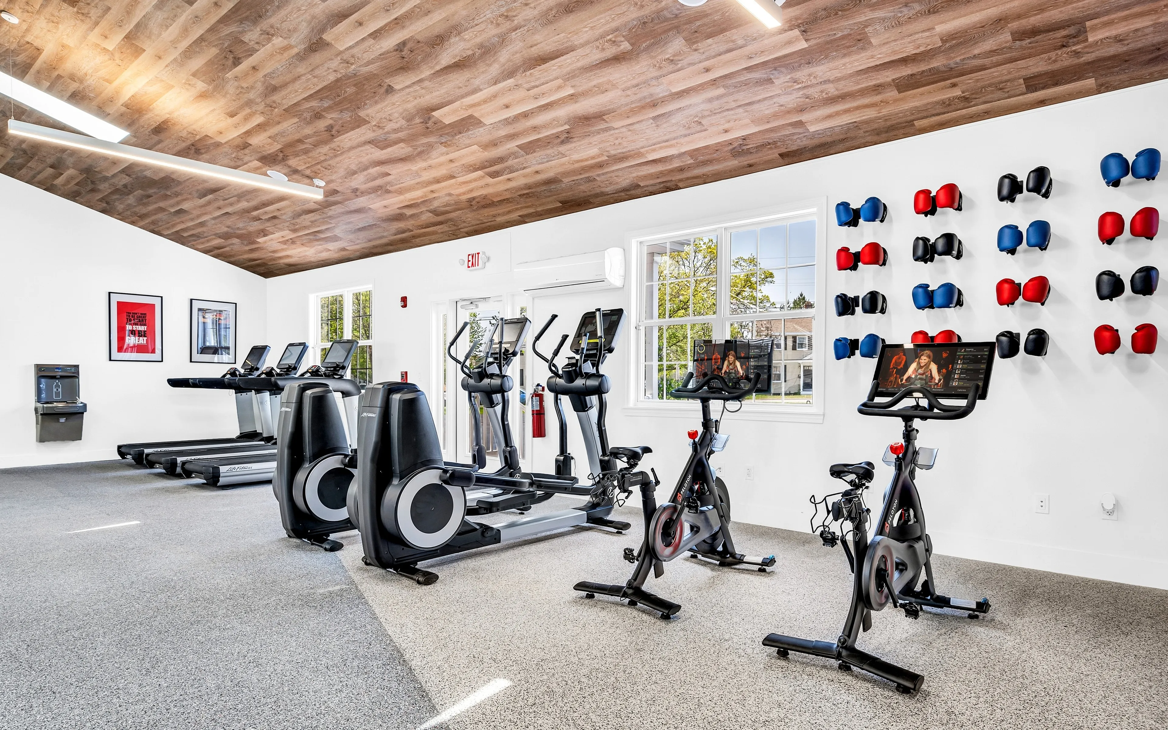 Modern gym with state-of-the-art equipment including treadmills, exercise bikes, and a stylish wall display of boxing gloves.