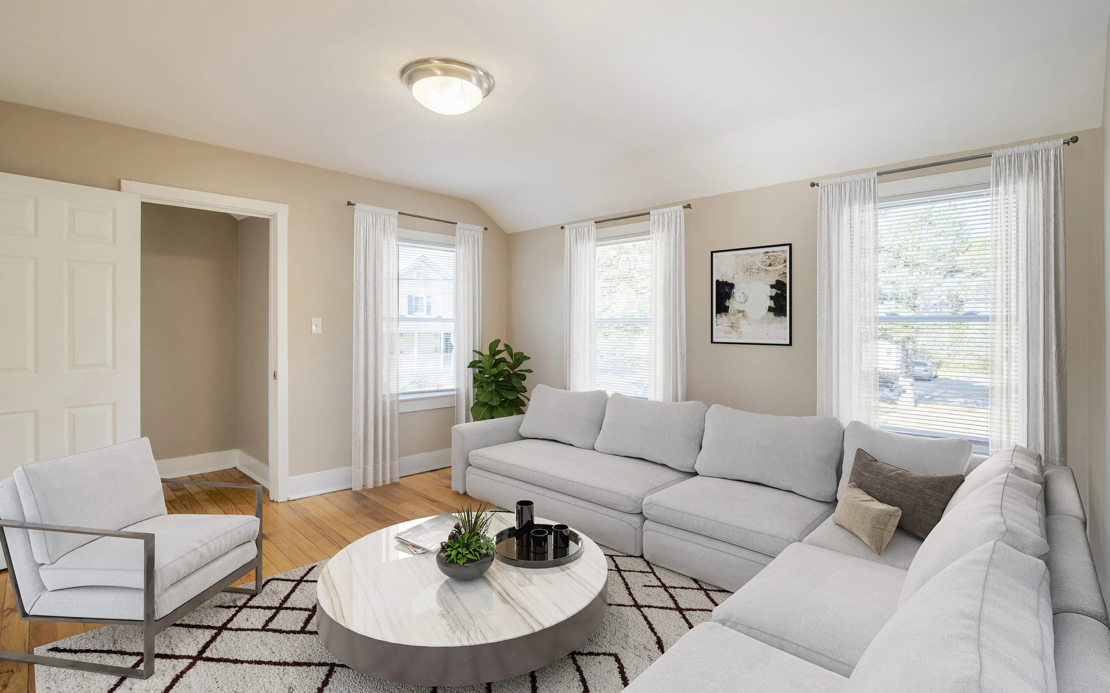Bright and inviting living room featuring a plush sectional sofa, chic armchair, and elegant round coffee table with contemporary decor.