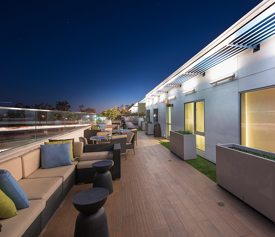 Elegant rooftop patio with cozy seating, modern decor, and stunning city views under a starry night.