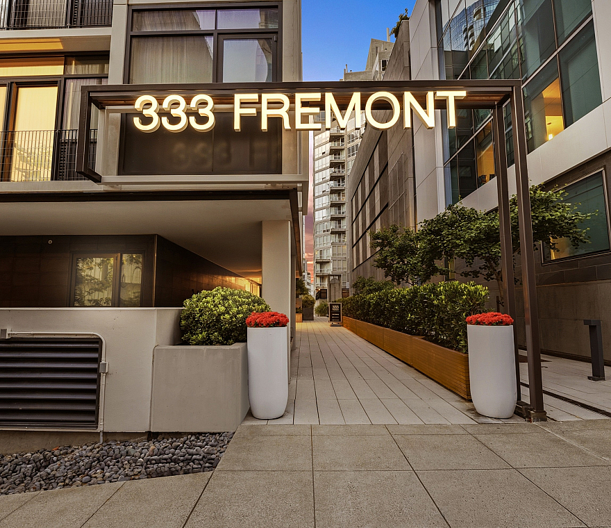 Modern entrance of 333 Fremont with elegant architecture and lush greenery, perfectly blending urban living with nature.