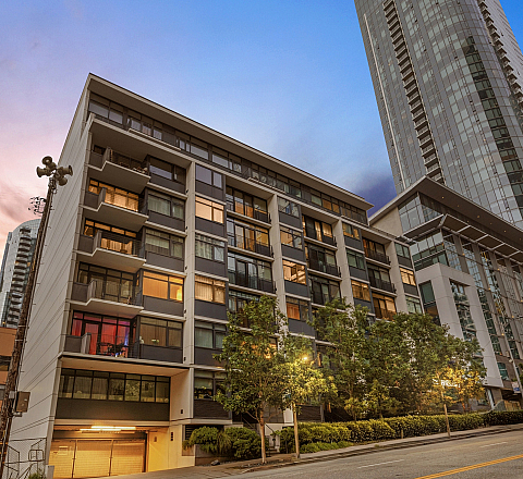 Modern urban apartment building with stunning city views at sunset, surrounded by sleek high-rises.