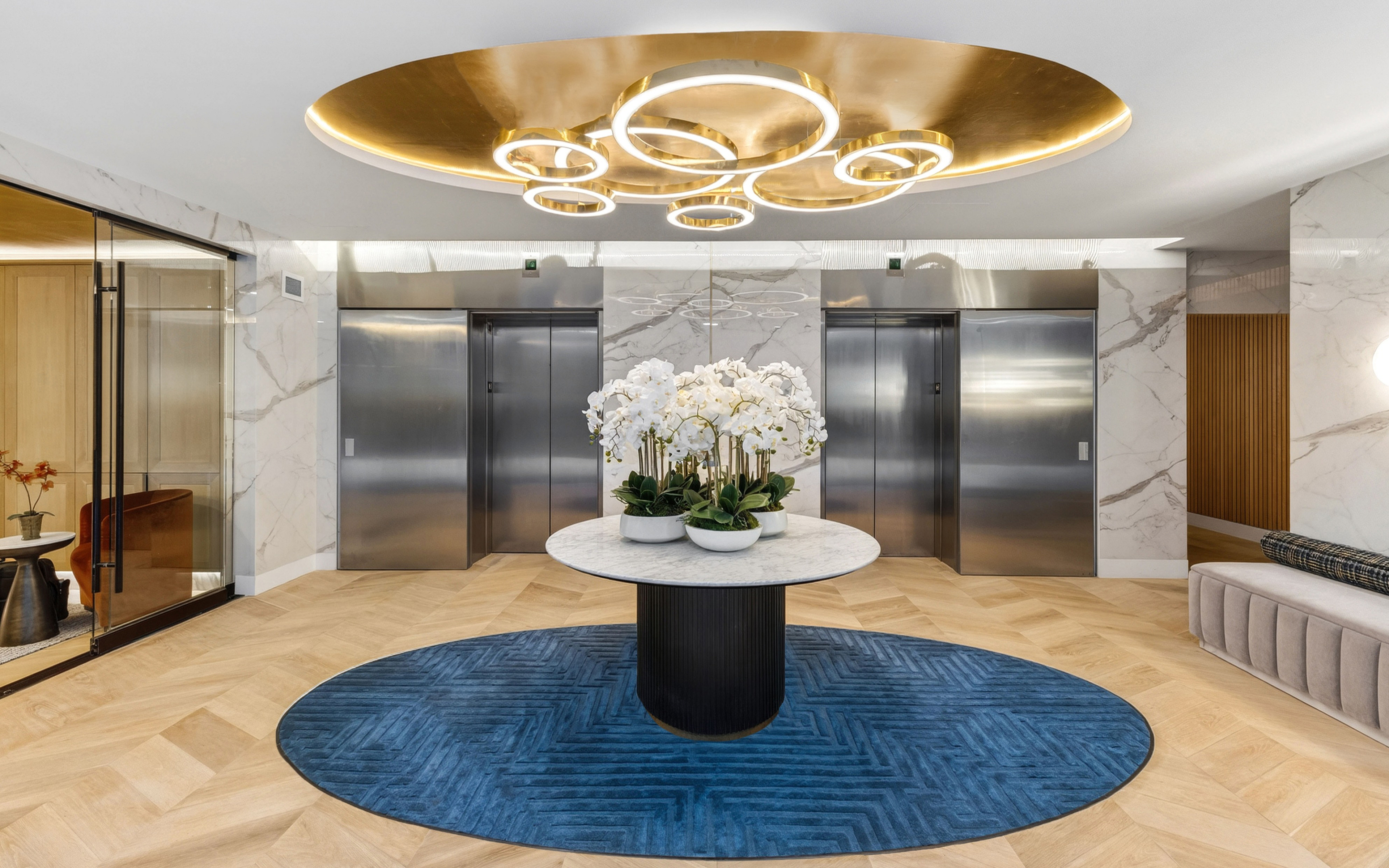 Luxurious lobby with elegant lighting, marble accents, and a stylish centerpiece featuring orchids and lush greenery.