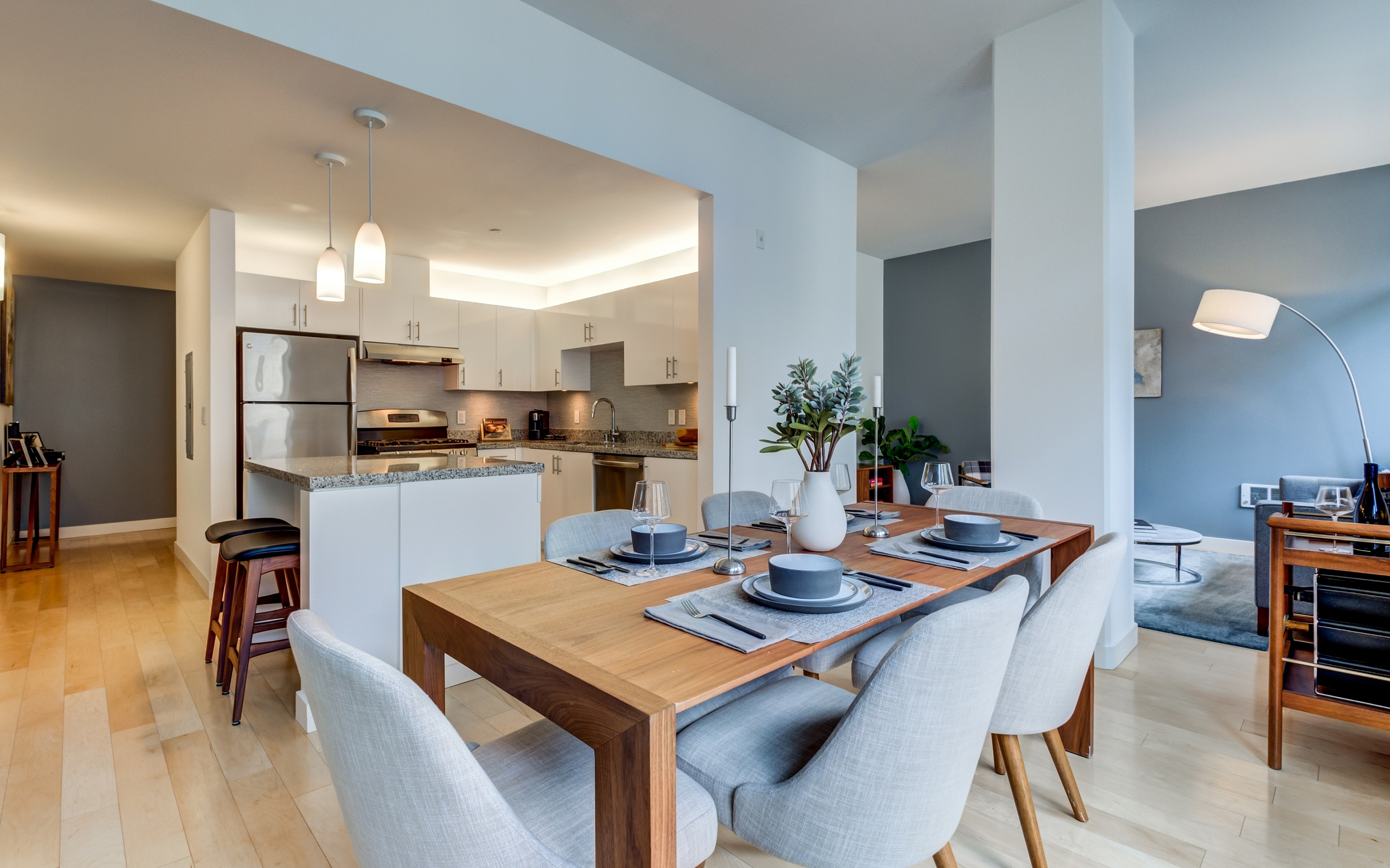 Modern open-plan kitchen and dining area with sleek finishes, featuring elegant lighting and a beautifully set wooden dining table.