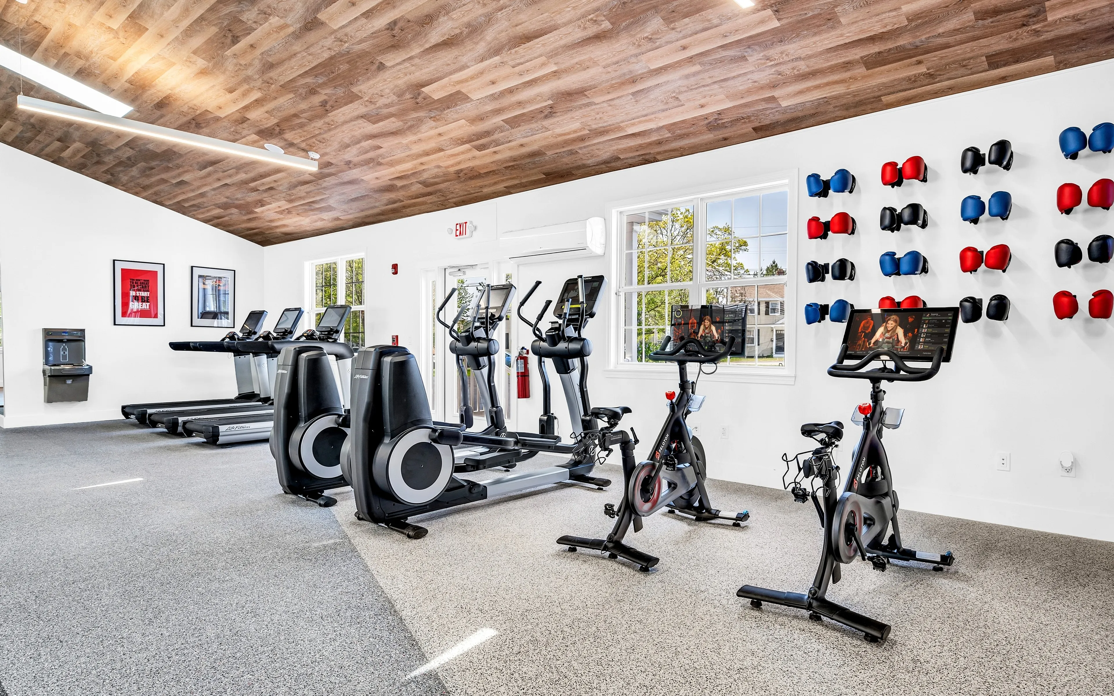 Modern fitness center with state-of-the-art exercise machines, stylish wood ceiling, and vibrant decor for an energetic workout environment.