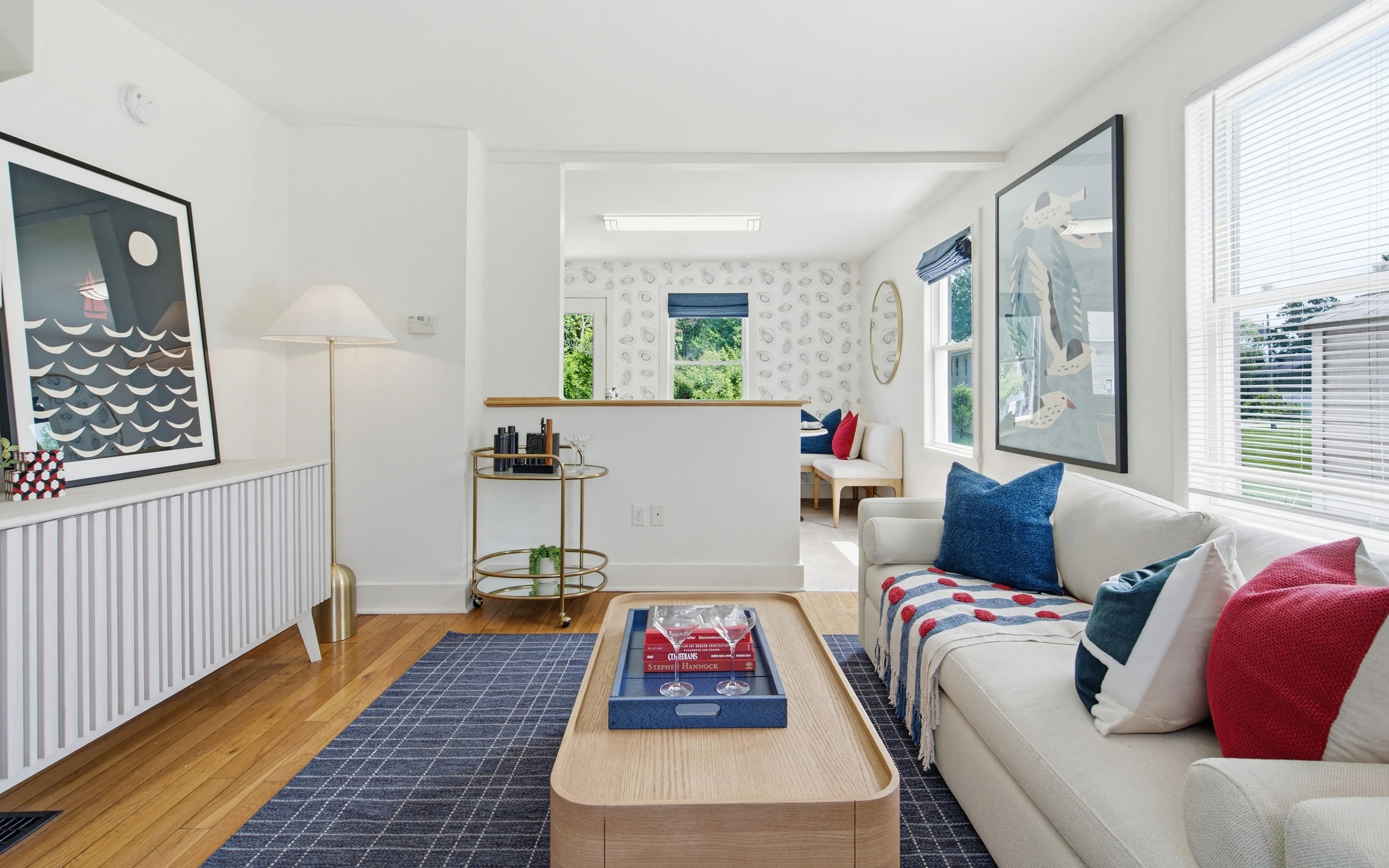 Bright and airy living room featuring modern decor, stylish artwork, and cozy seating area with colorful cushions.