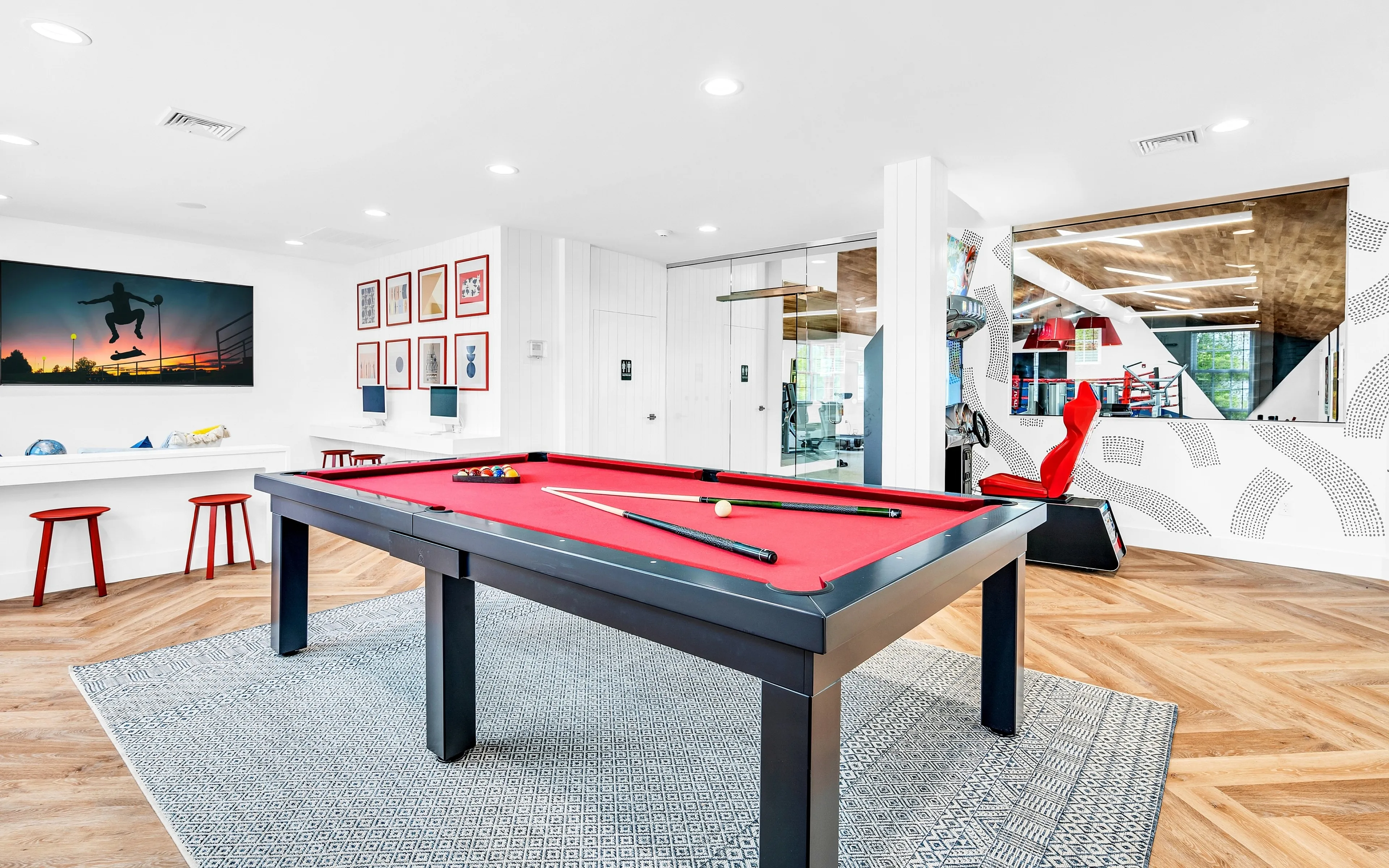 Bright recreational area featuring a sleek red pool table, modern decor, and vibrant artwork, perfect for entertainment and relaxation.