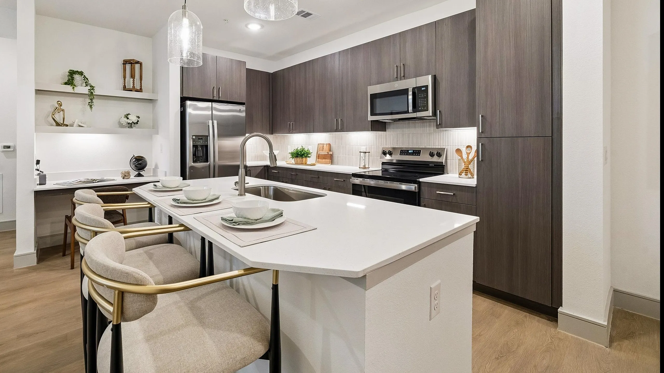 Modern kitchen with elegant gray cabinetry, sleek stainless steel appliances, and a spacious island with stylish pendant lighting.