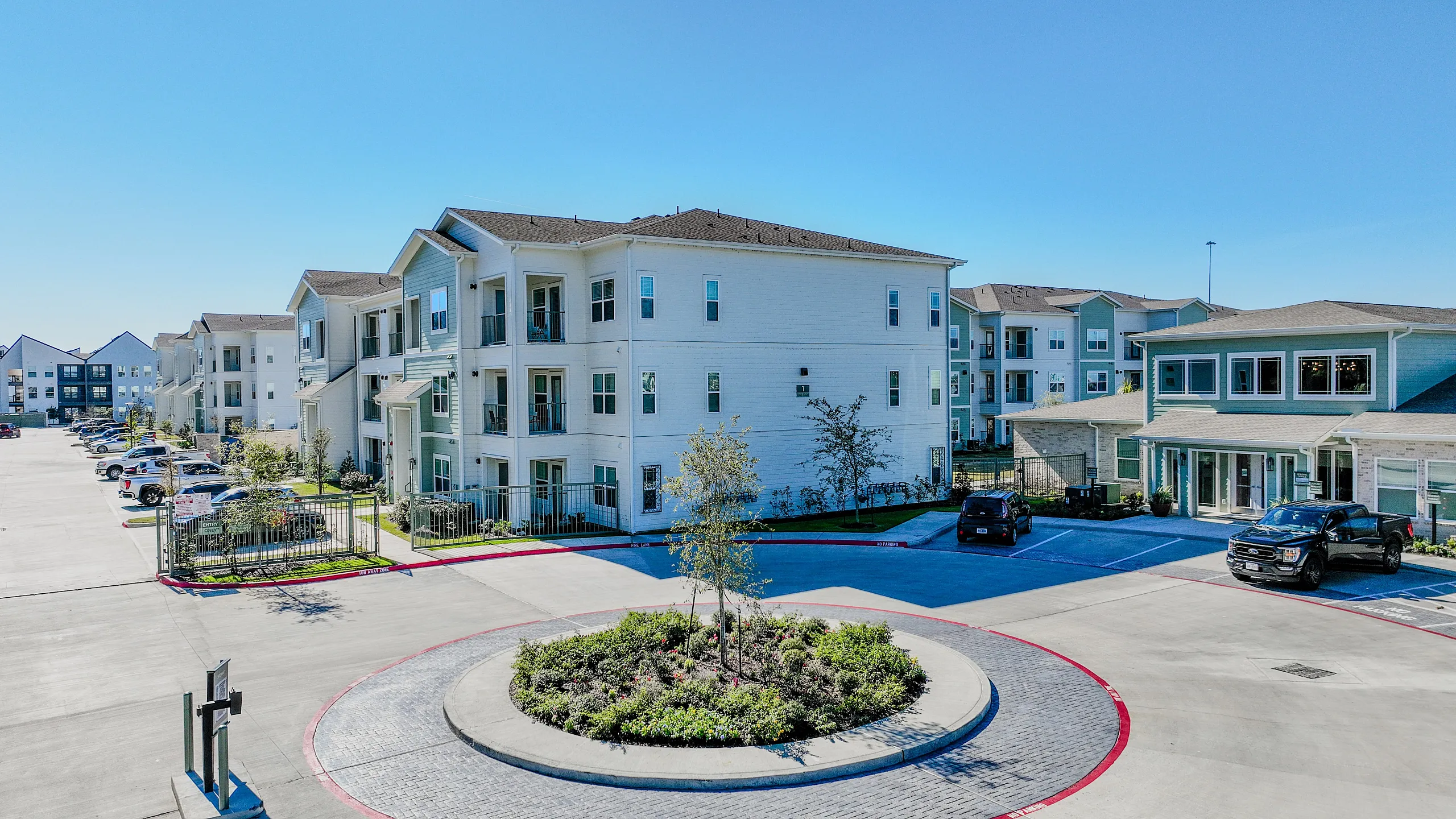 Modern apartment complex with spacious balconies and beautiful landscaping, featuring ample parking and contemporary architecture.