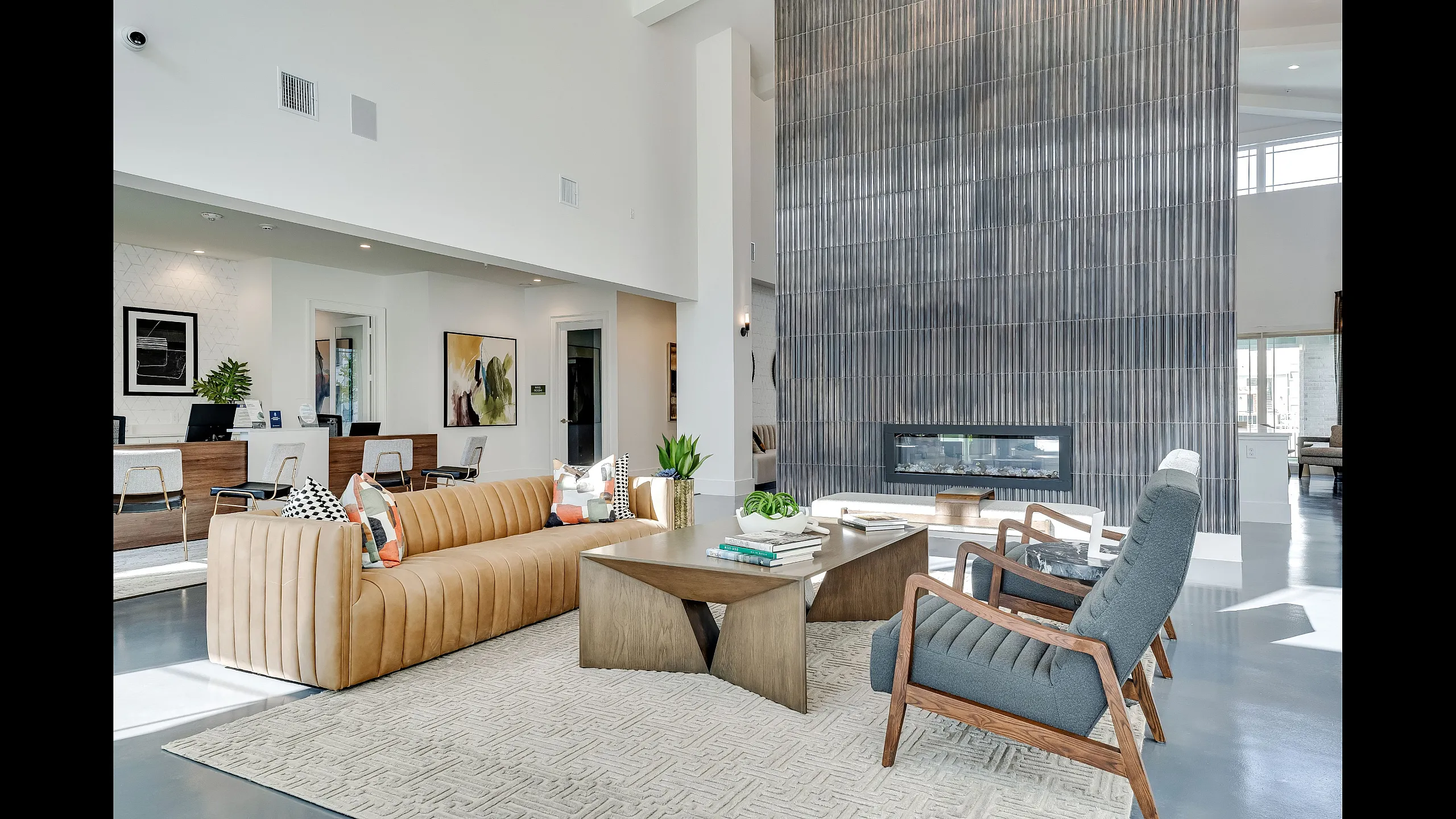 Modern living room featuring a chic beige sofa, stylish gray armchairs, and a contemporary fireplace. The room is filled with natural light and accentuated by minimalist decor, creating an inviting atmosphere.