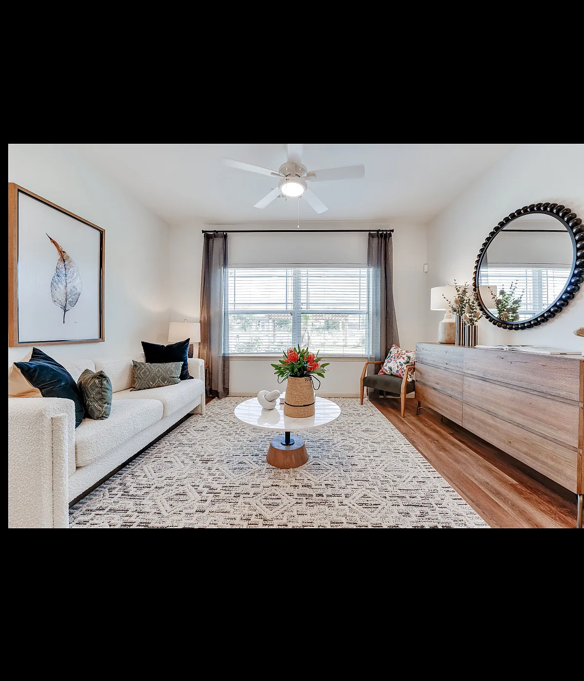Bright and inviting living room with a cozy sofa, chic decor, wooden accents, and abundant natural light streaming through large windows.