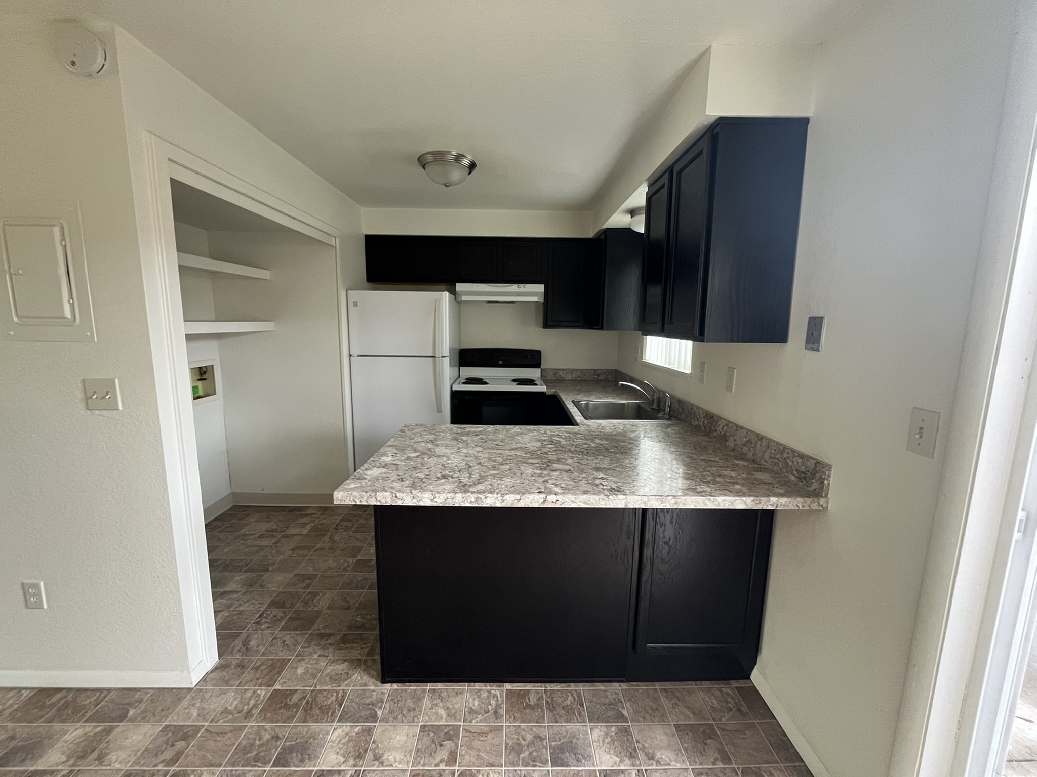 Modern kitchen with sleek black cabinets, granite countertops, and a compact open shelving area enhancing functionality.
