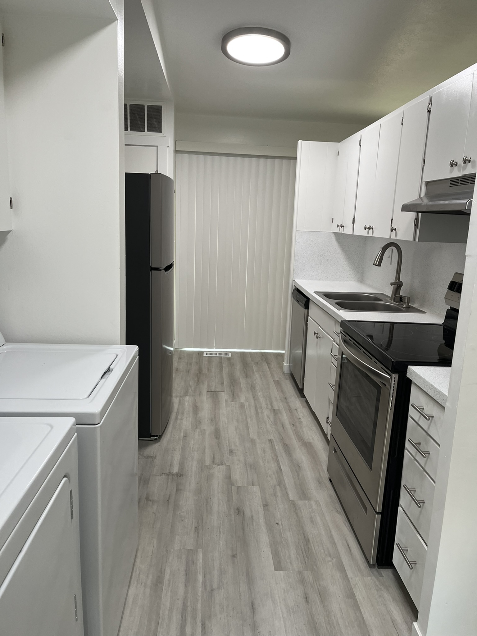 Contemporary kitchen with sleek stainless-steel appliances, modern cabinetry, and elegant wood flooring, perfect for culinary enthusiasts.