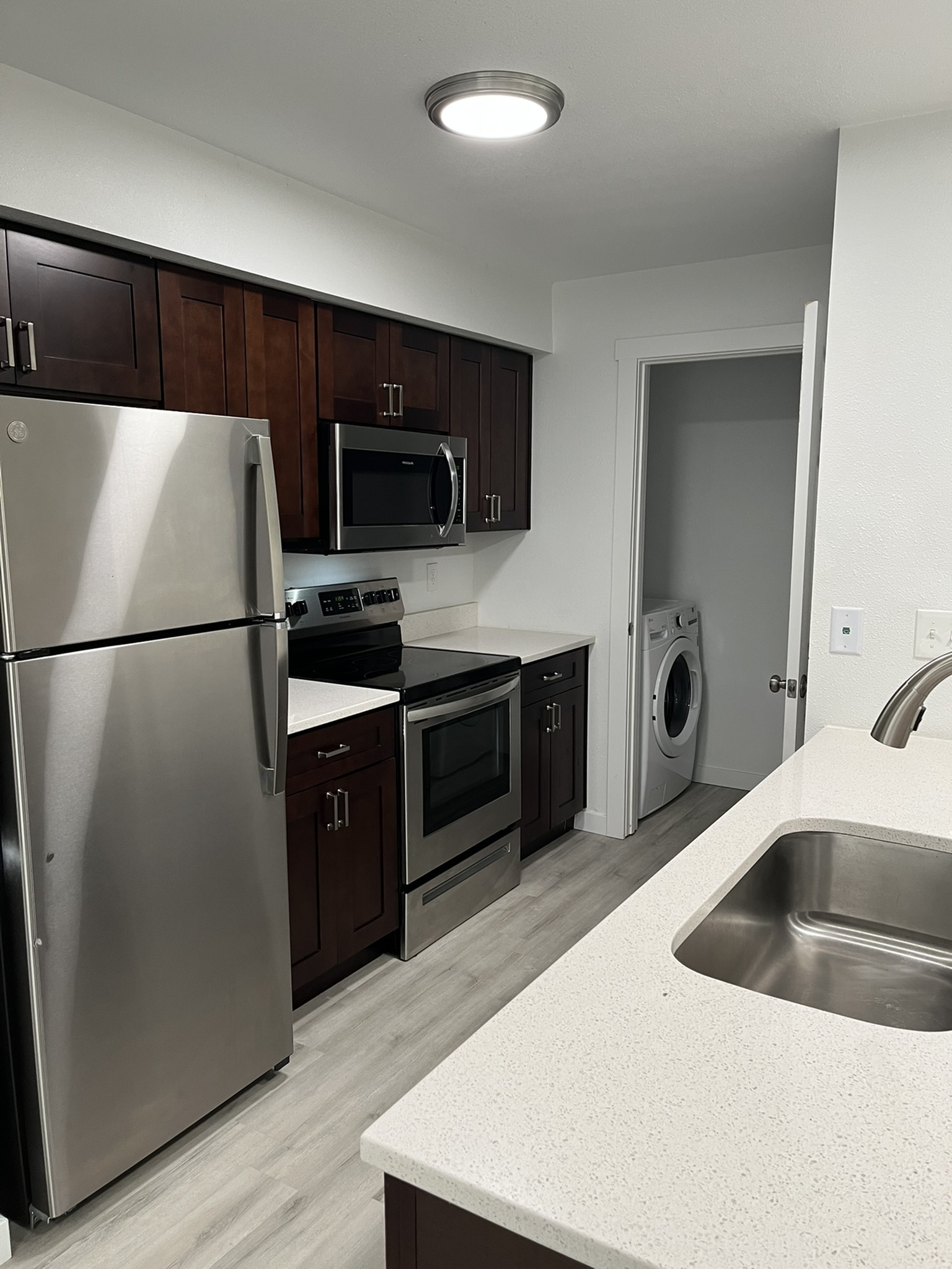 Modern kitchen featuring stainless steel appliances, sleek cabinetry, and an adjacent laundry area with contemporary flooring.