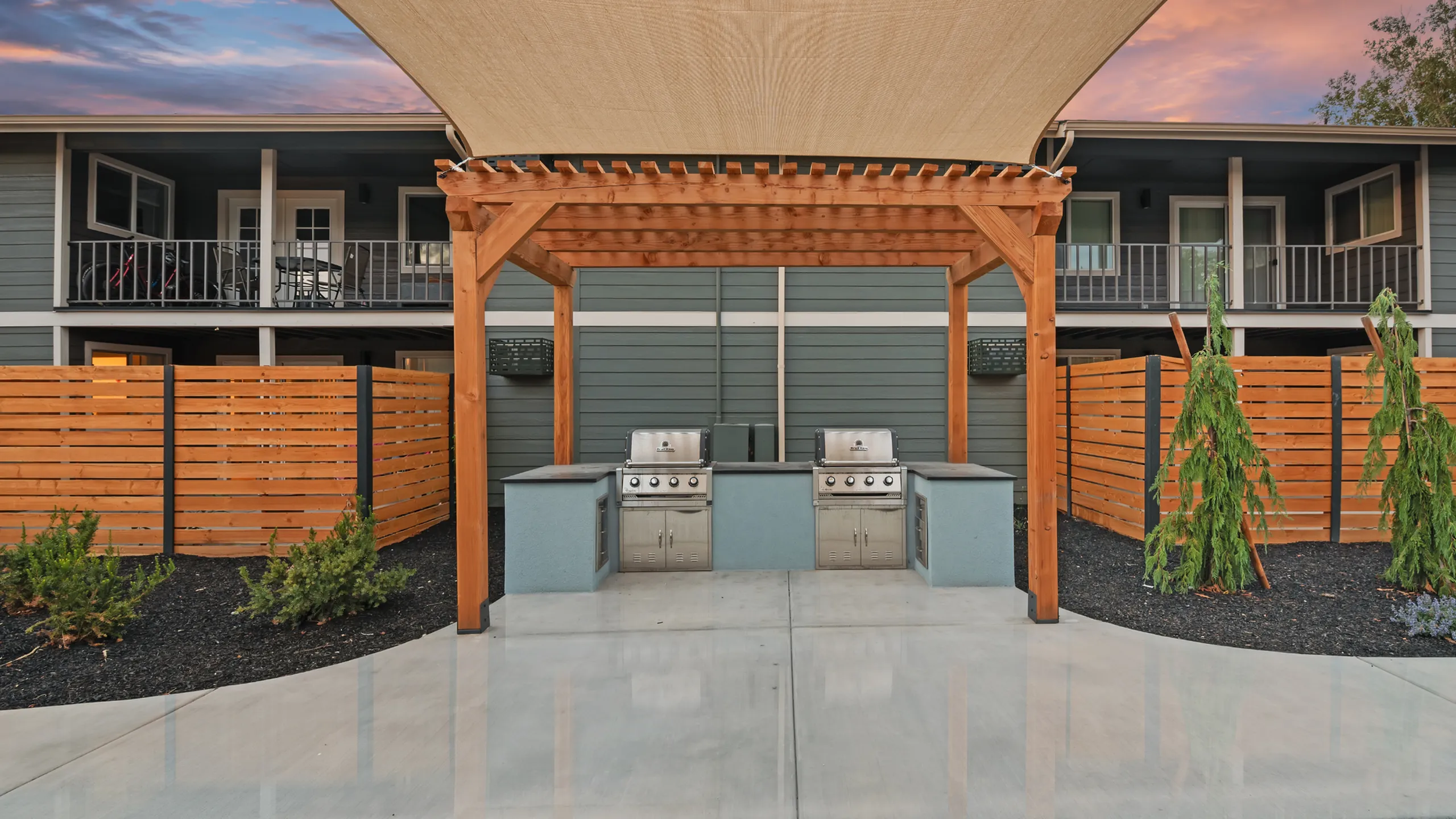 Charming outdoor BBQ area with sleek grills set beneath a stylish pergola, perfect for entertaining in a modern apartment complex.