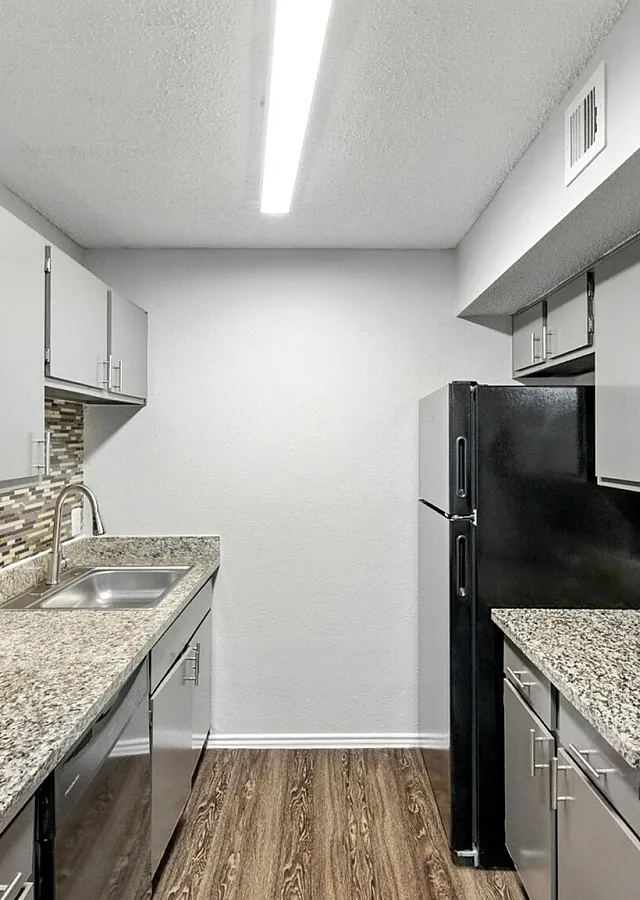Sleek modern kitchen with granite countertops, stainless steel appliances, and elegant mosaic tile backsplash.