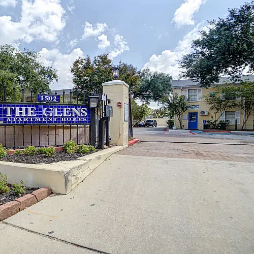 Inviting entrance of The Glens Apartment Homes, showcasing a welcoming sign and vibrant greenery, perfect for new residents seeking move-in specials.