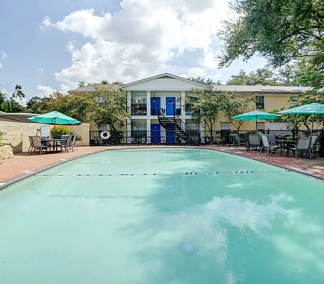 Inviting outdoor pool area with comfortable seating and lush greenery, perfect for relaxation and sunshine.