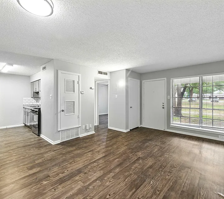 Bright and inviting open-plan living area with modern laminate flooring, showcasing a sleek kitchen with contemporary appliances and large windows offering tranquil views.