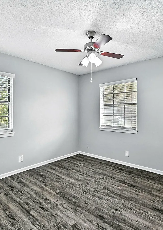 Bright and inviting bedroom with large windows, neutral gray walls, and elegant wood-like flooring, perfect for a serene retreat.