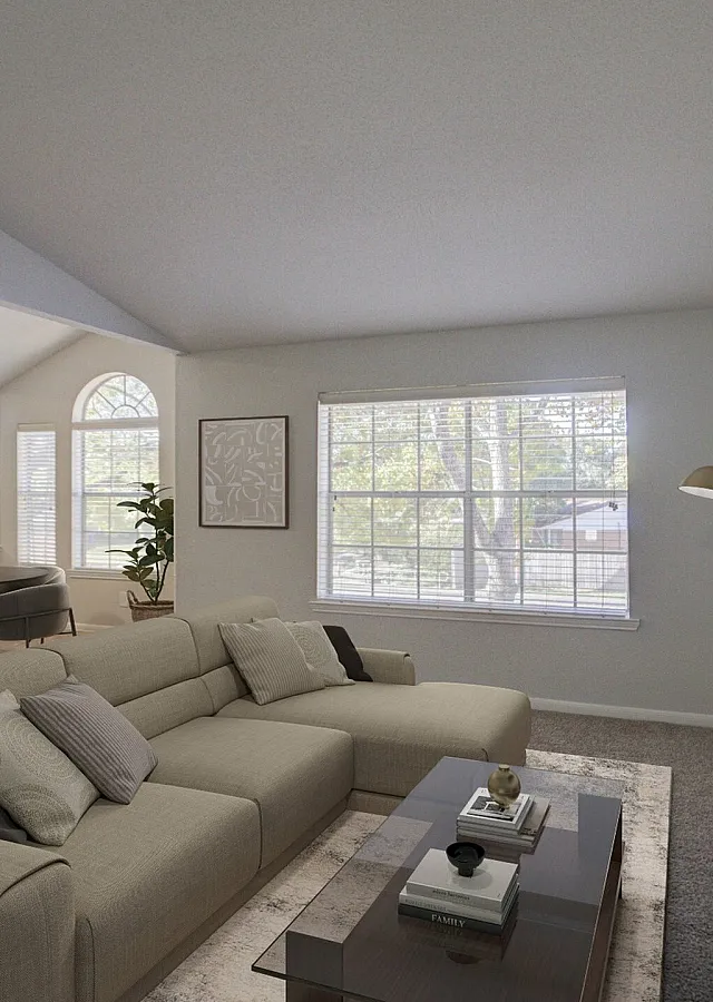 Inviting living room with plush beige sofa, mounted flat-screen TV, and large windows offering abundant natural light.