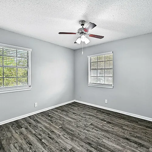 Bright and airy bedroom with modern wood flooring, neutral walls, and large windows offering serene garden views.