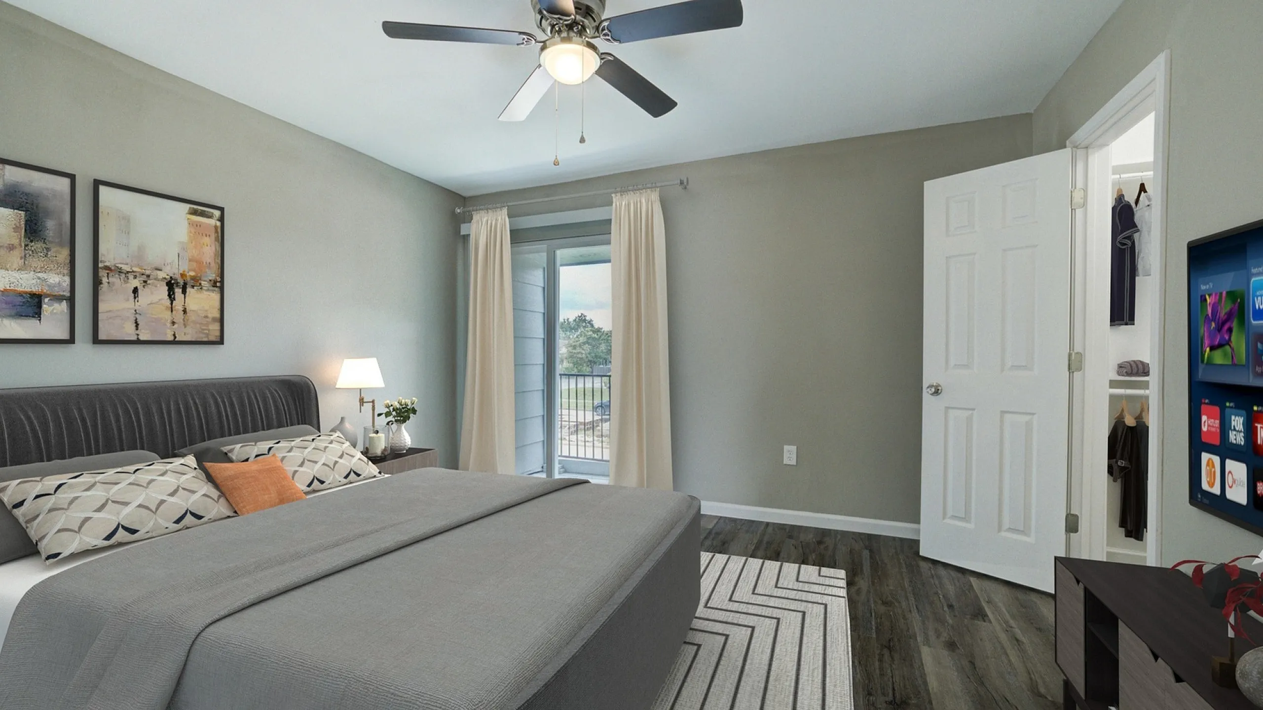 Modern bedroom featuring a stylish bed with patterned pillows, elegant artwork, and a ceiling fan, leading to a bright balcony with serene views.