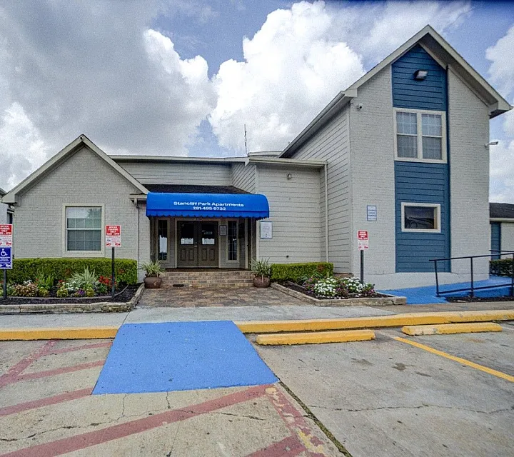 Inviting apartment complex entrance with a charming blue awning and well-maintained landscaping, creating a welcoming atmosphere.
