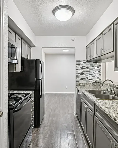 Sleek modern kitchen with chic granite countertops, elegant gray cabinetry, and stylish mosaic backsplash.