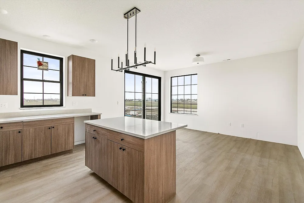 Bright and modern kitchen with sleek wooden cabinets, spacious island, and large windows offering scenic views, perfect for contemporary living.