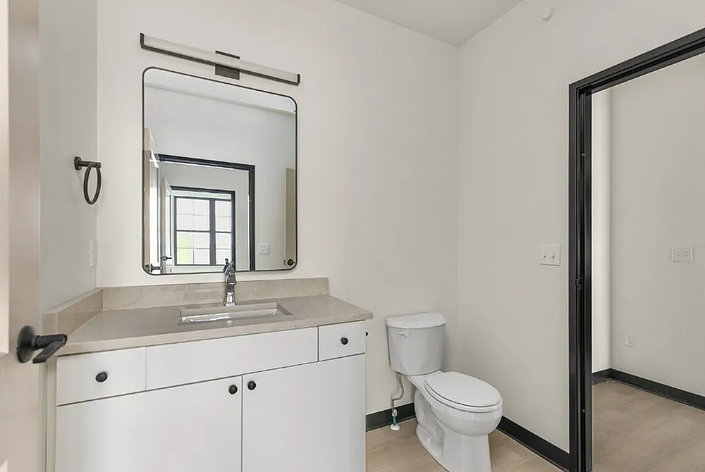 Contemporary bathroom with sleek vanity, spacious countertop, and large mirror, highlighted by natural light.