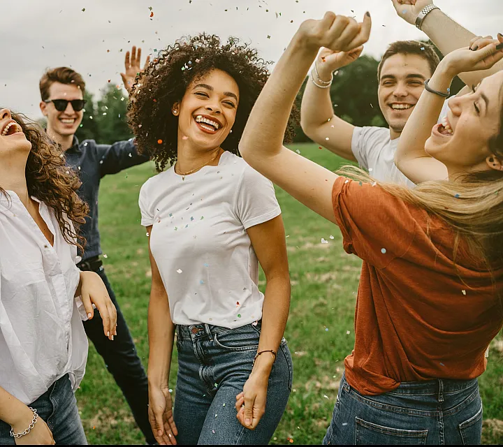 Group of Friends Dancing in Field with Confetti
