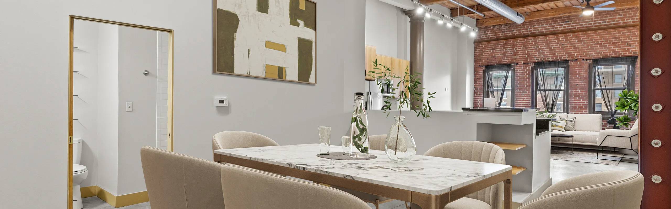 Contemporary loft dining area with chic marble table, elegant seating, and industrial-style exposed beams.