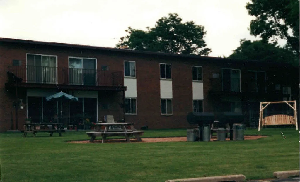Inviting apartment complex featuring lush green lawns, picnic tables, and a charming outdoor swing.