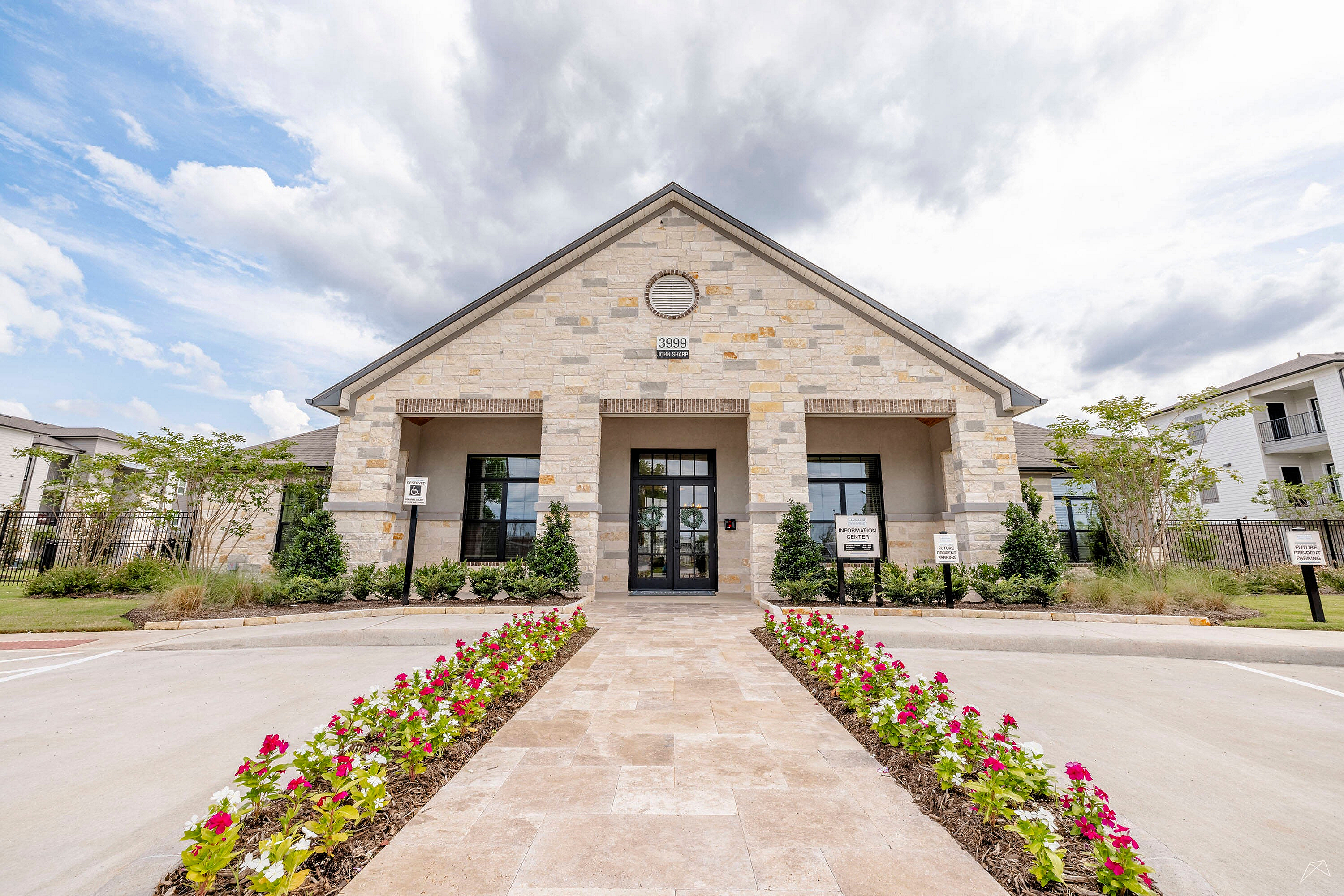 Charming stone facade of an apartment complex, beautifully adorned with vibrant flowers and lush greenery.