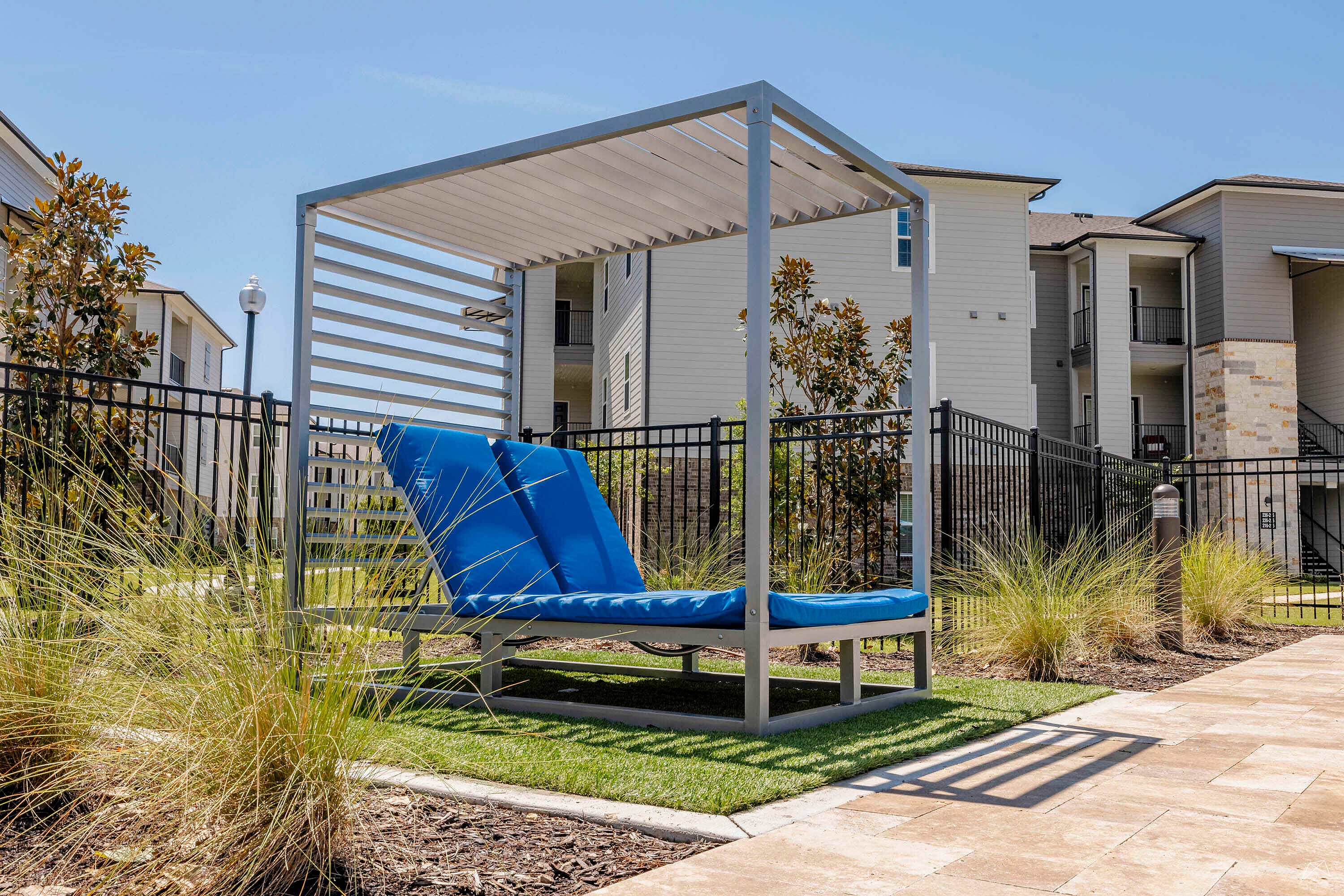 Inviting outdoor area featuring modern lounge seating under a stylish pergola, perfect for relaxation amidst lush greenery.