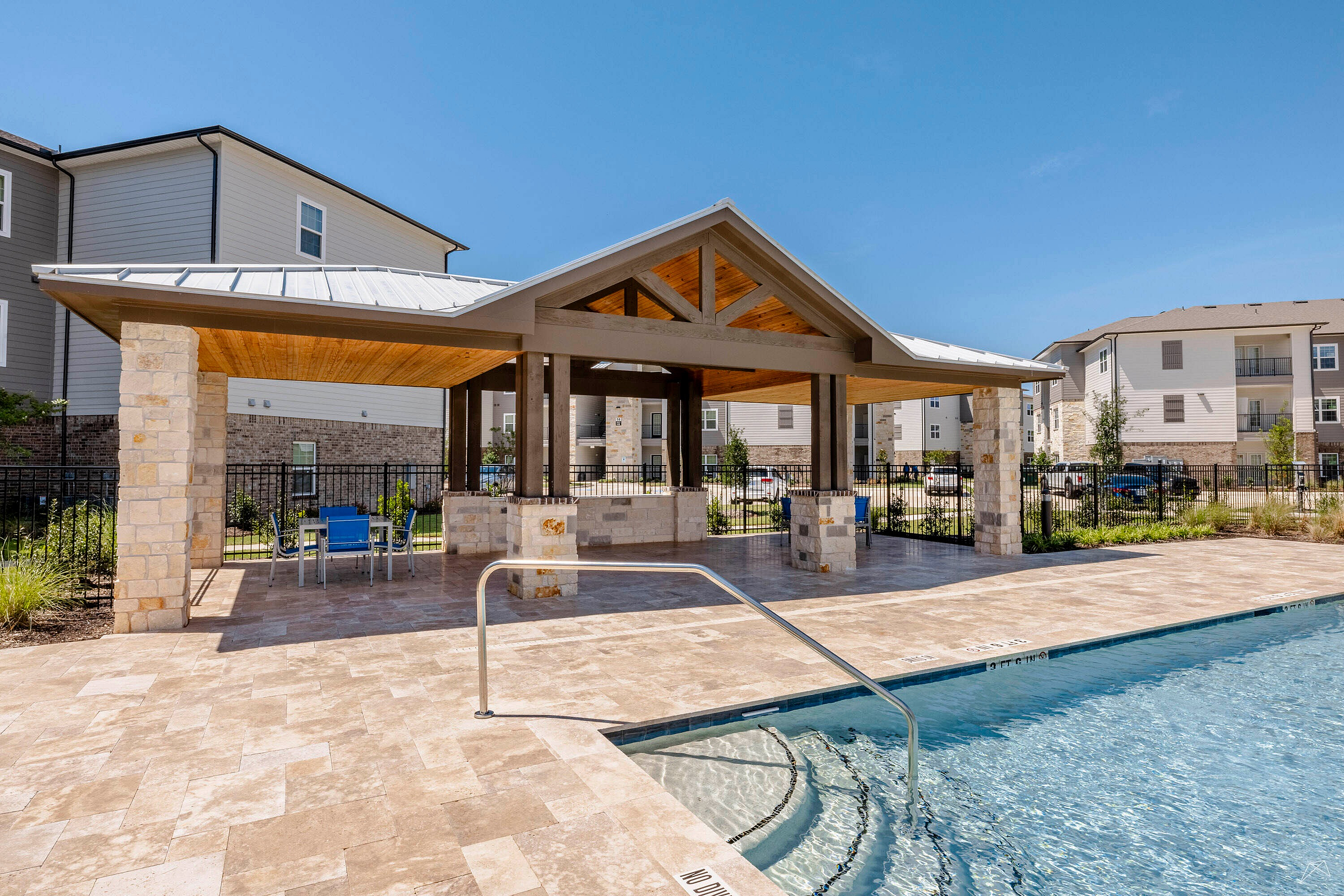 Inviting outdoor pool area with a stylish pergola and modern apartment backdrop, perfect for relaxation and social gatherings.