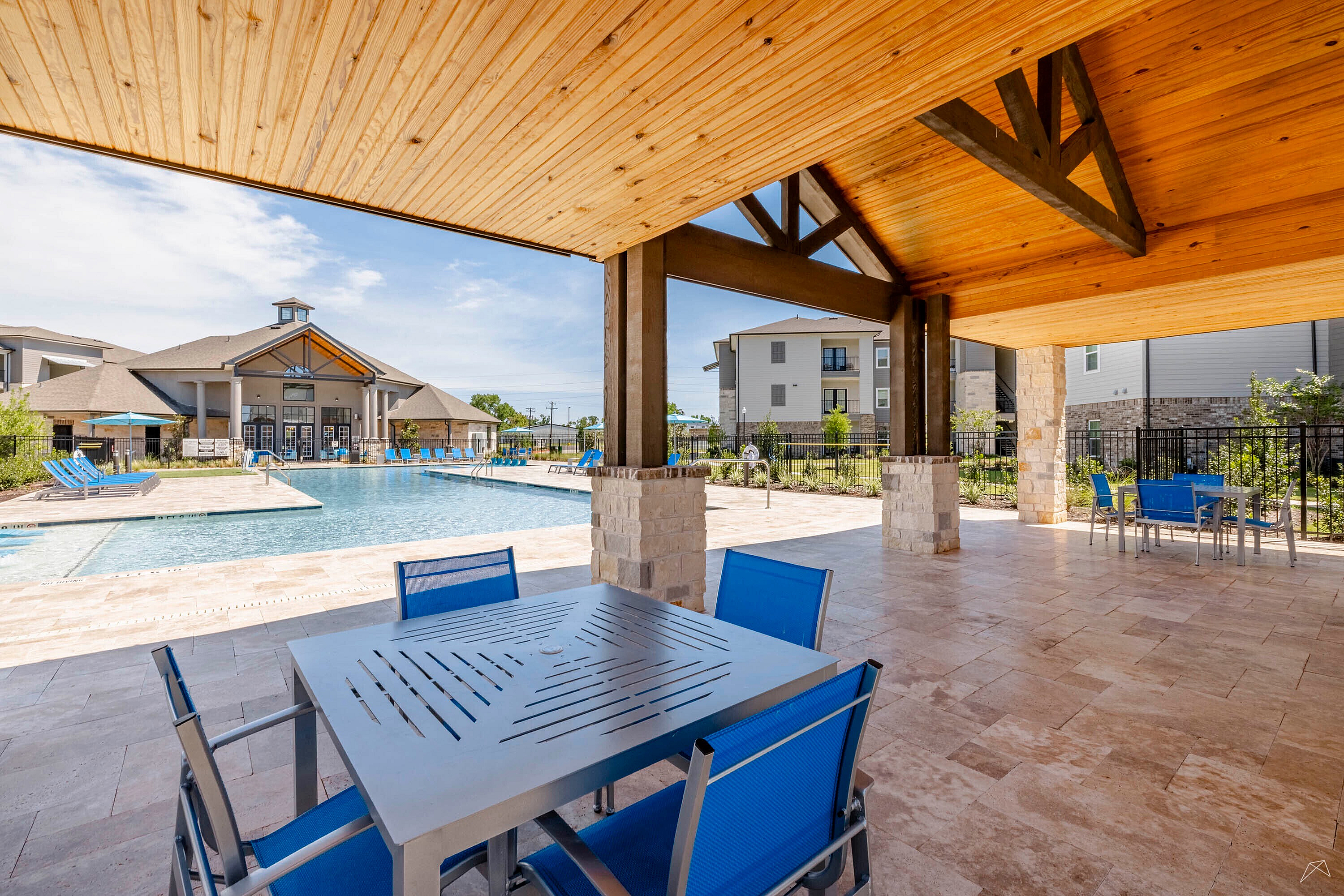 Inviting outdoor space with modern patio seating overlooking a pristine swimming pool and contemporary apartment complex.