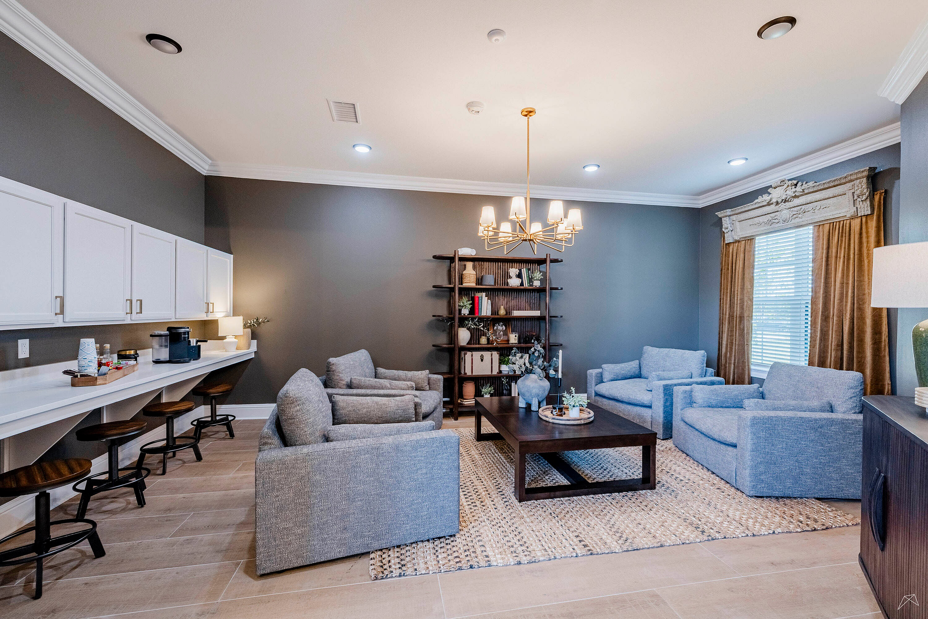 Elegant living space with modern gray seating, chic chandelier, spacious counter seating, and stylish shelving.