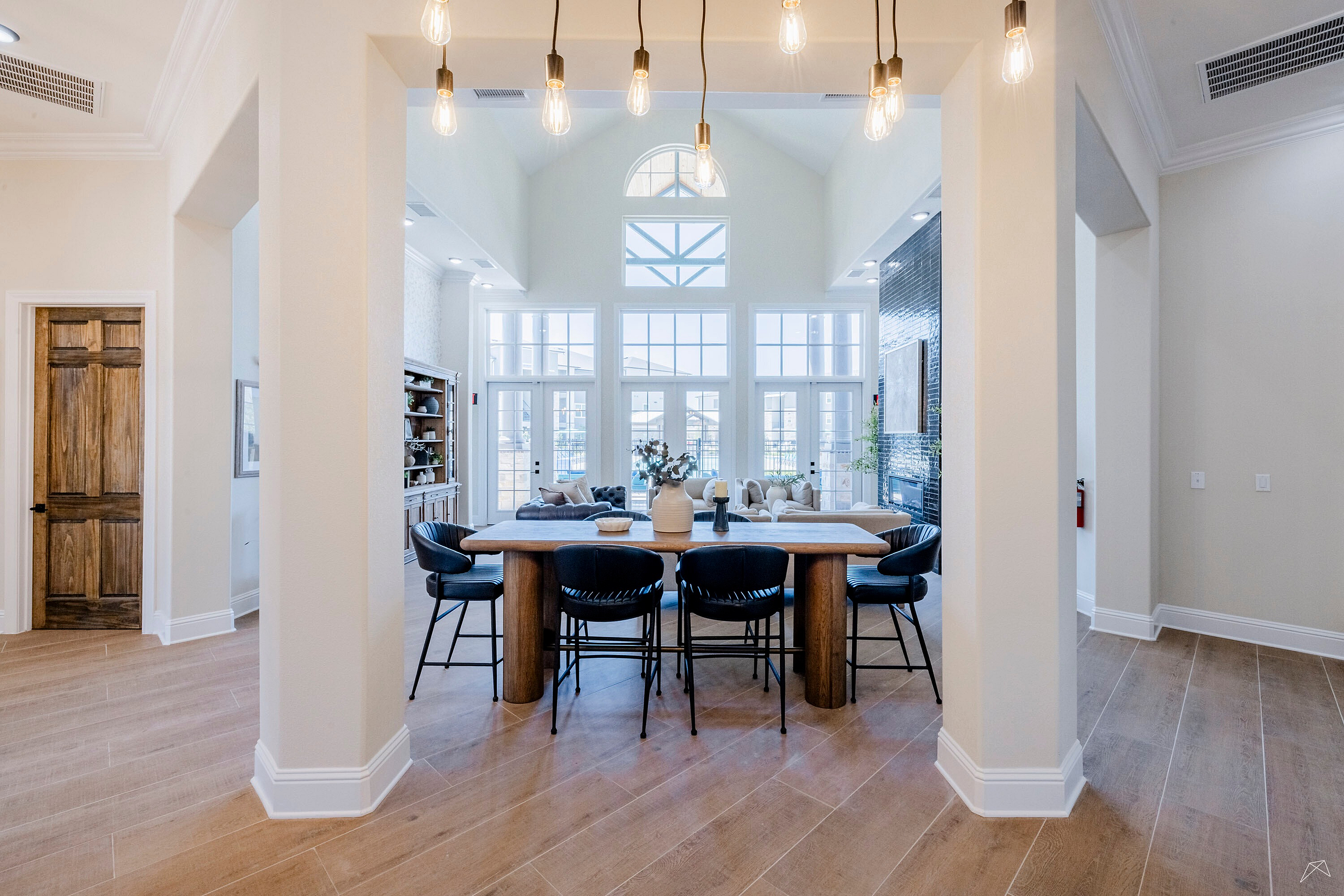 Bright and airy living space with high ceilings, elegant pendant lighting, expansive windows, and a cozy seating area.